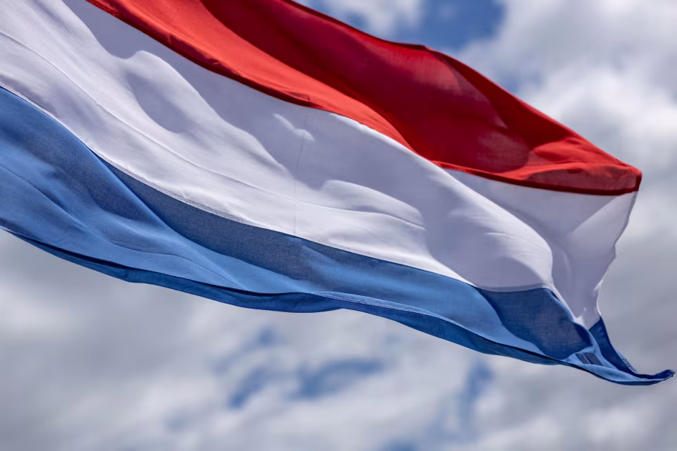 Wapperende Nederlandse vlag tegen een bewolkte lucht