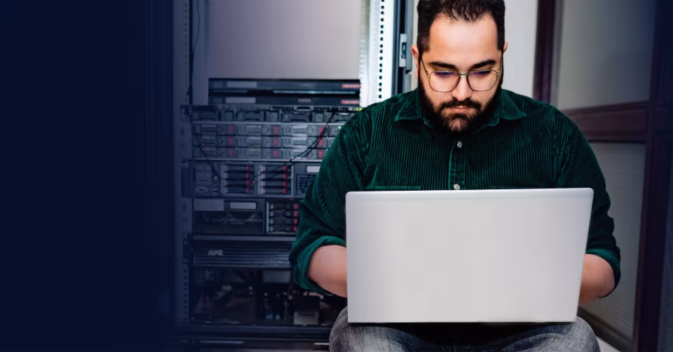 Man met bril werkt op een laptop voor een serverkast