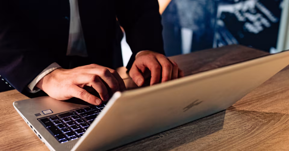Handen typen op een laptop op een houten tafel