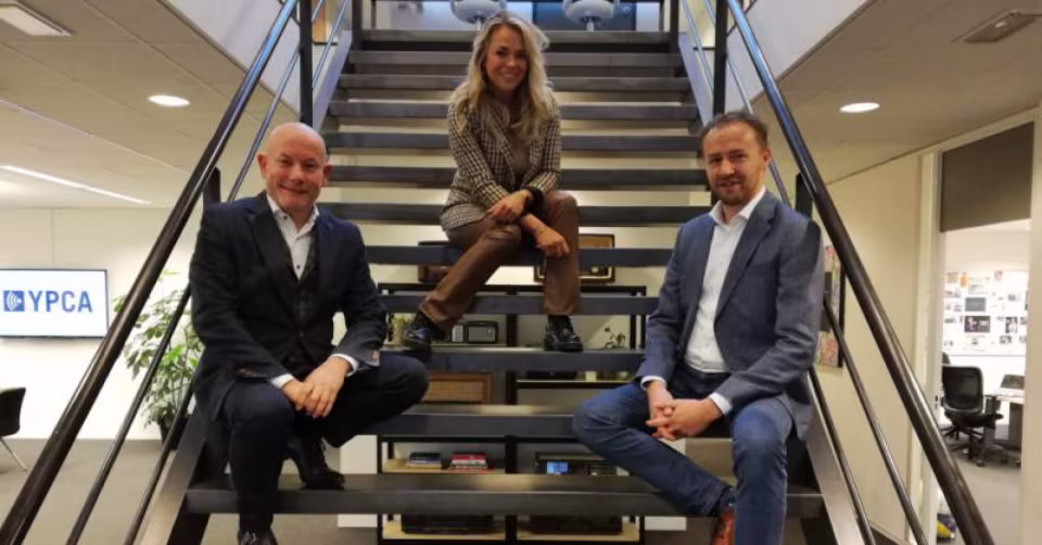 Twee mannen en een vrouw zitten op een trap in een kantoor