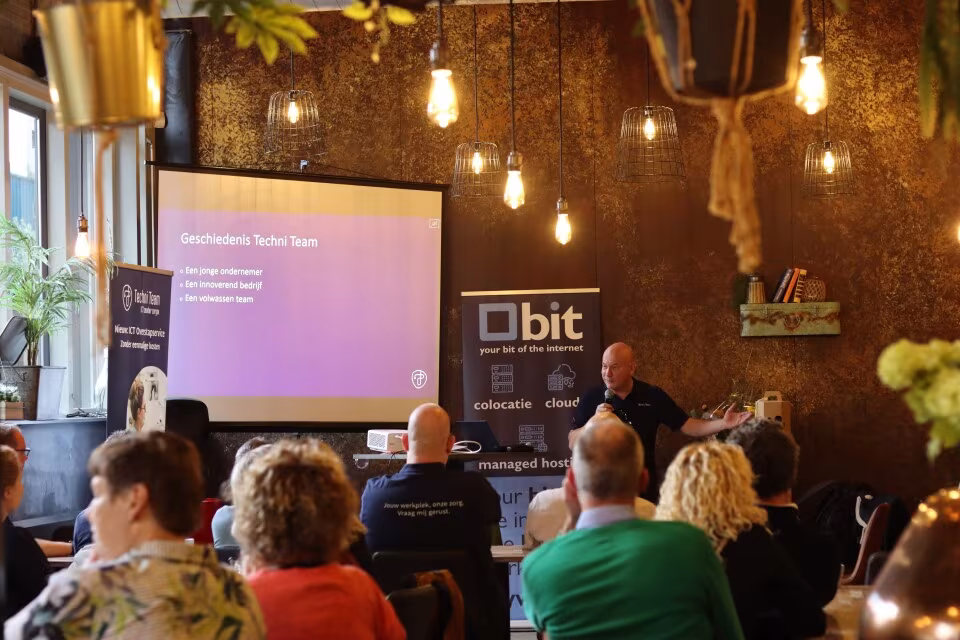 Presentatie over de geschiedenis van Techni Team voor een zaal met publiek tijdens het jubileum