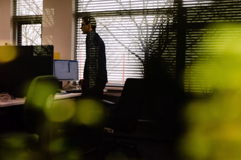 Silhouet van een collega die in een kantoor bij het raam staat, tussen planten