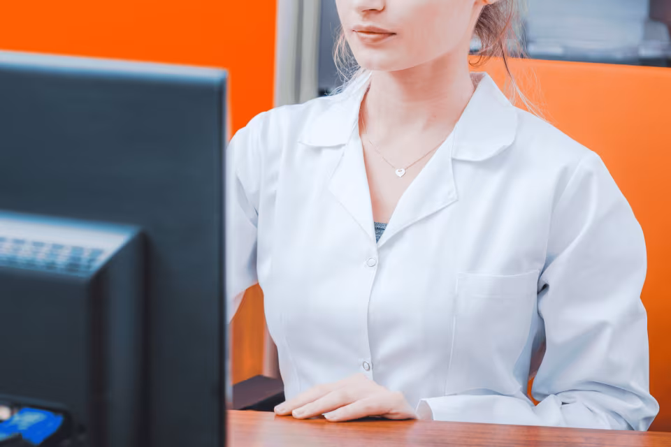 Medewerker in witte jas zit achter een computerscherm