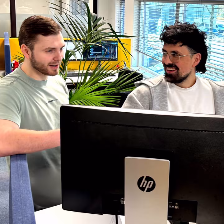 Twee collega’s van Techni Team overleggen achter een beeldscherm