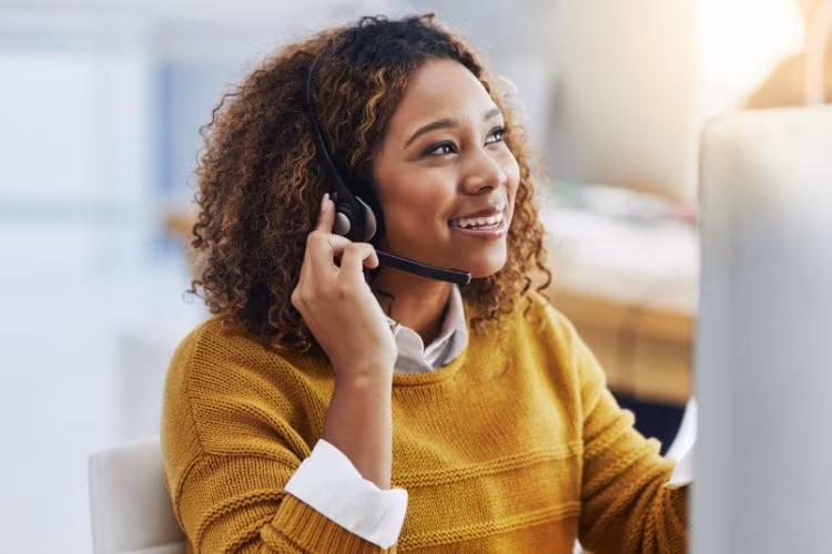 Lachende assistente met headset kijkt opzij naar haar scherm